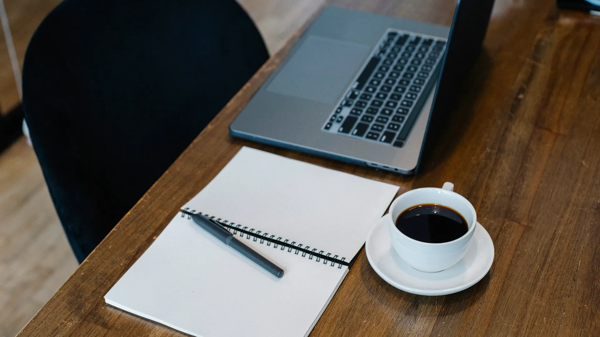 Laptop, notebook and coffee on a tidy desk