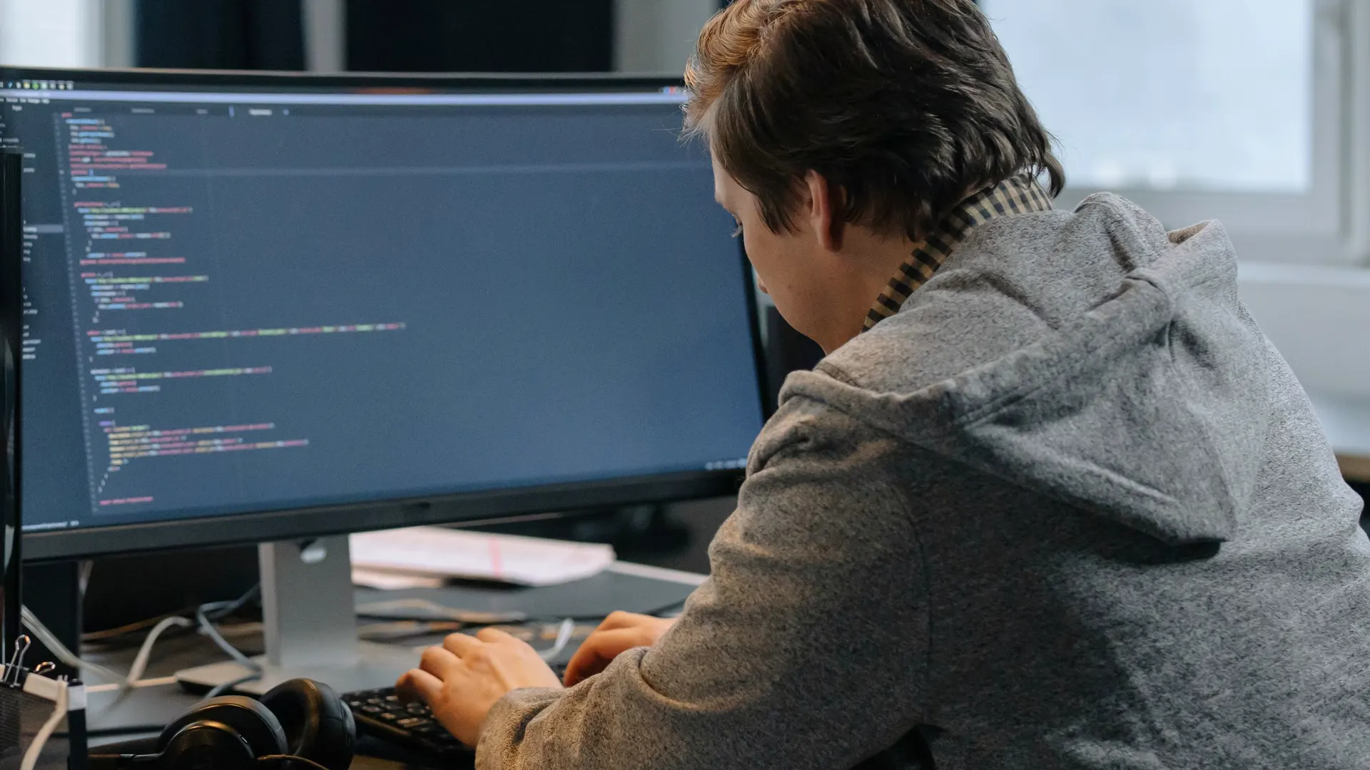Developer writing code at a desk with large monitors
